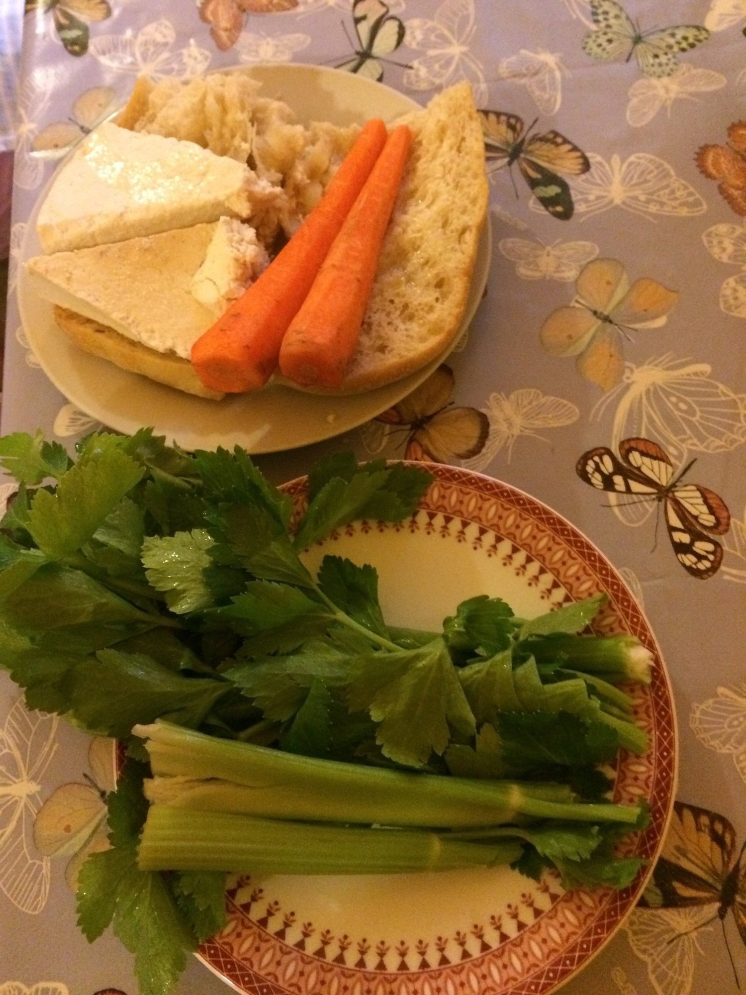 Bread, cheese, carrots and fresh celery lie on two plates at a farm in Sardinia.