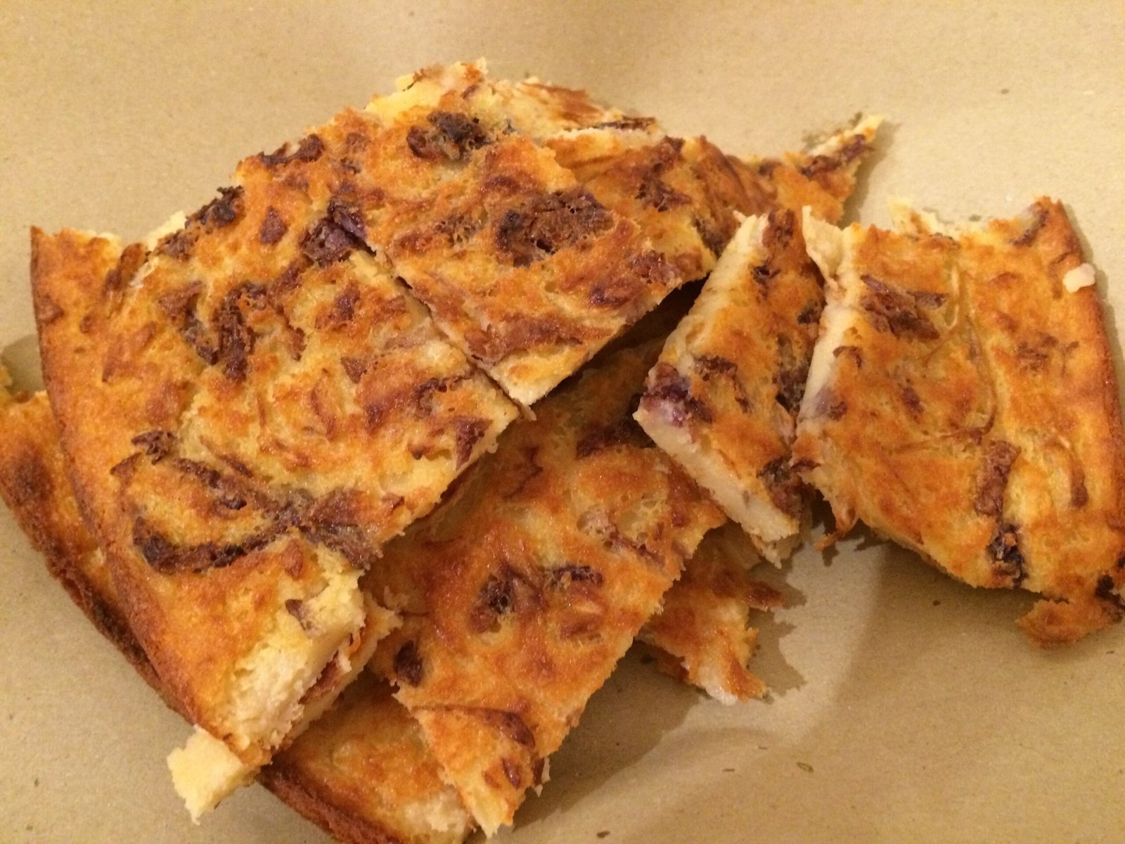 Slices of baked flatbread with onions lie on a plate in Sardinia.