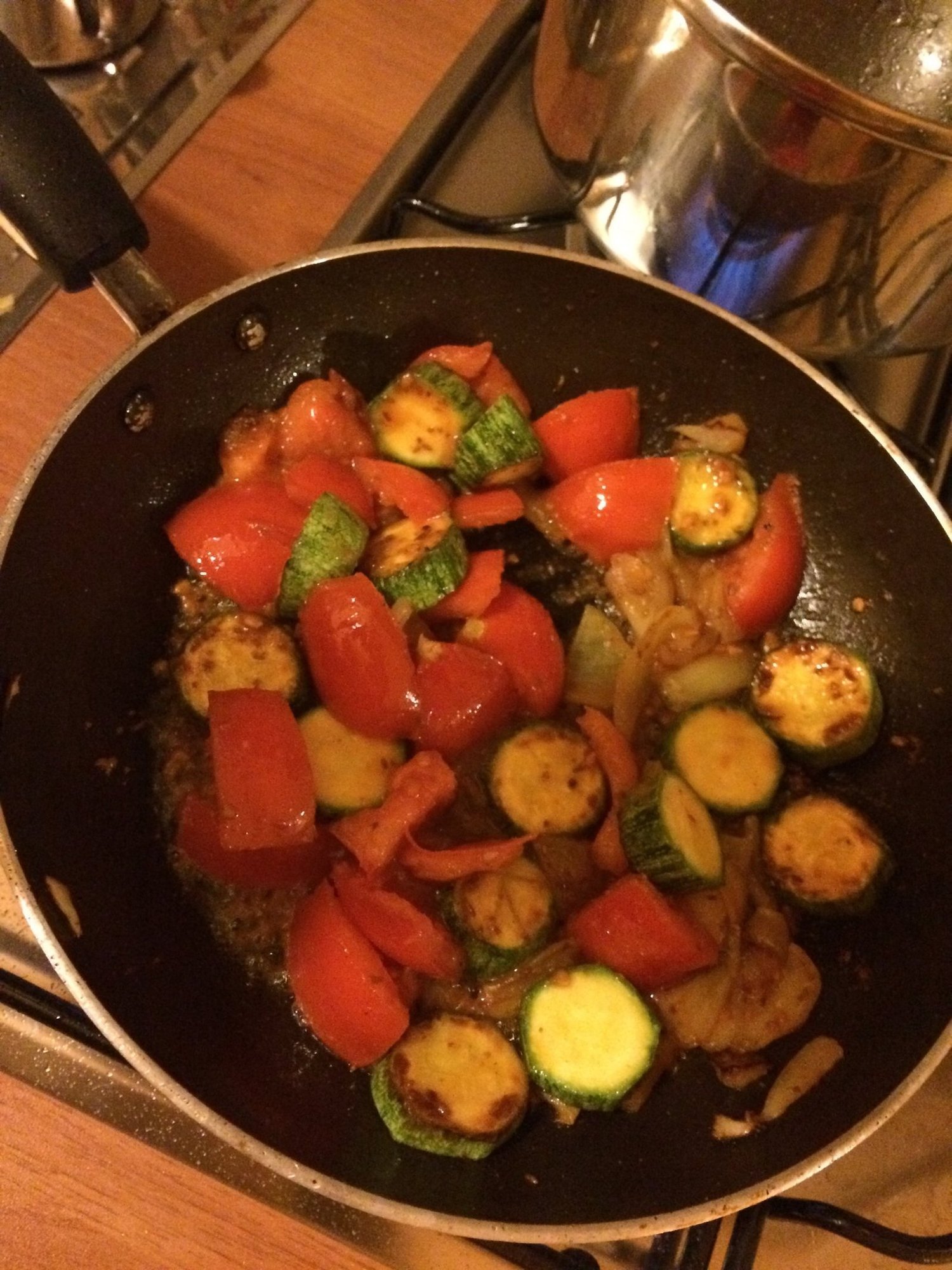 Red peppers and zucchini cook in a frying pan in a kitchen in Sardinia.