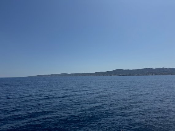 Long island on the horizon across the deep blue Saronic Gulf