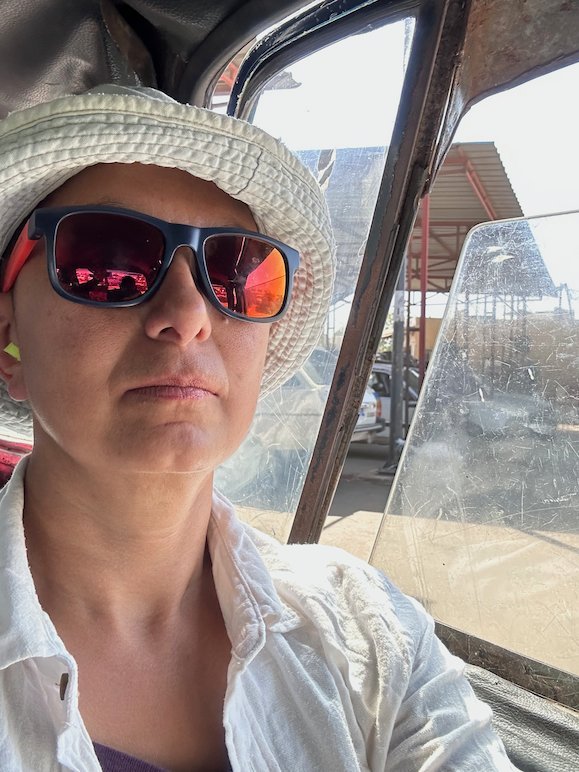 Zayera Khan in a white hat takes a selfie inside a bush taxi.