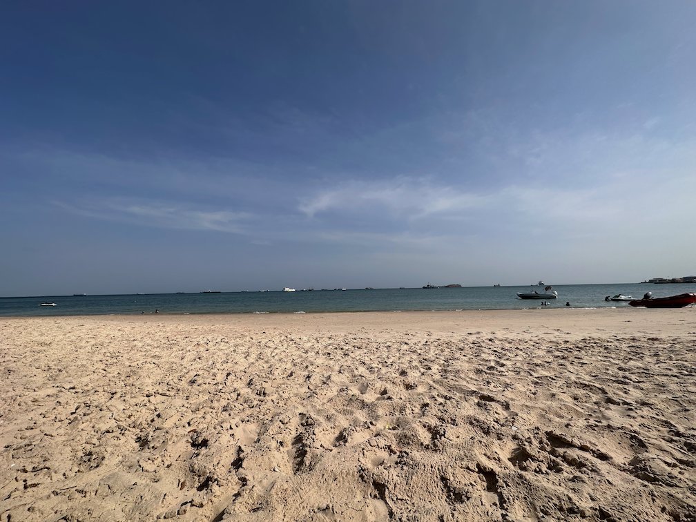 A calm sandy beach with small boats on the water in Senegal.
