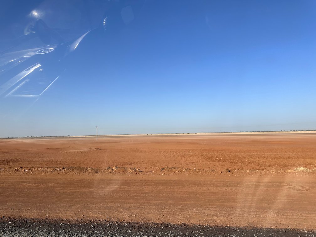 A flat red plain lies under a blue sky in Senegal.