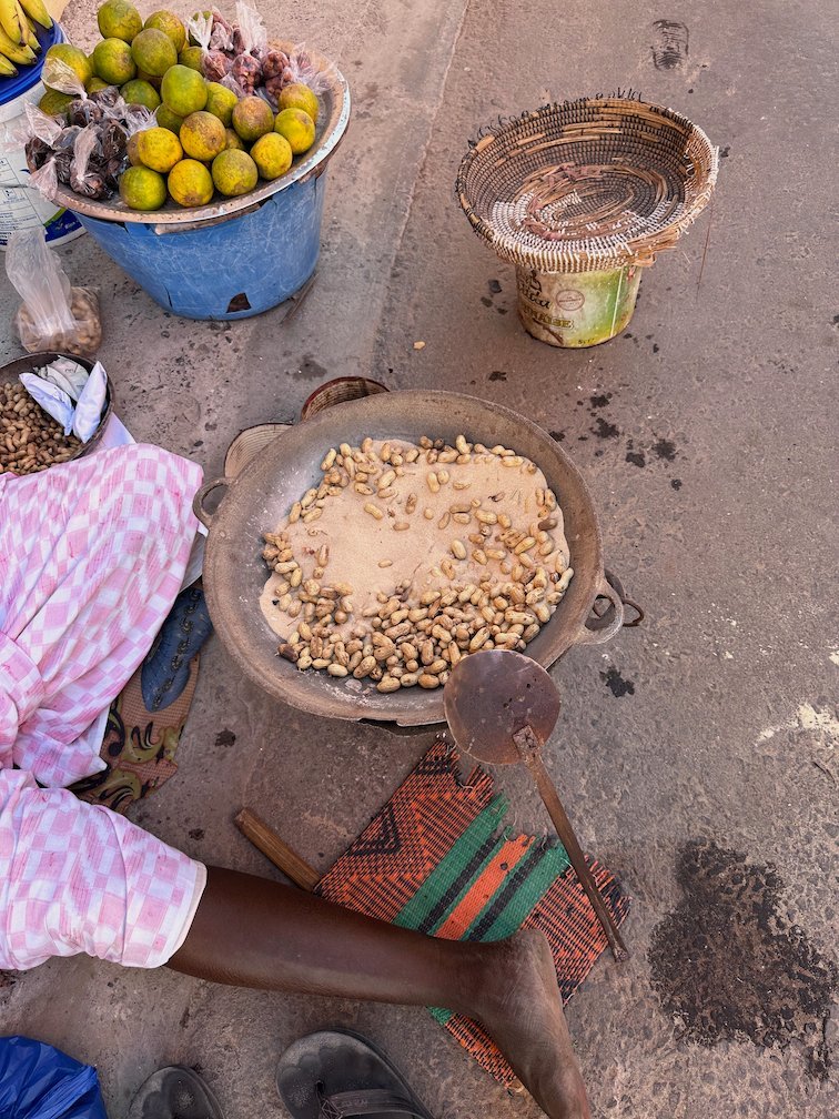 A street vendor roasts peanuts in a pan of hot sand.