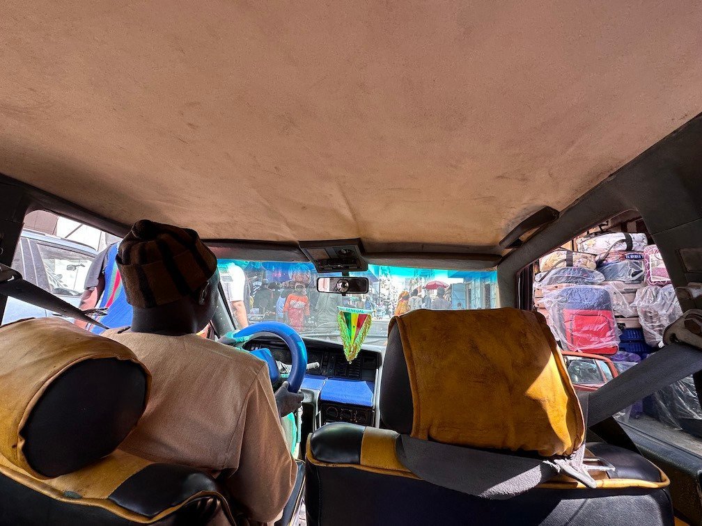 A passenger sits in the front of an old shared taxi in Senegal.