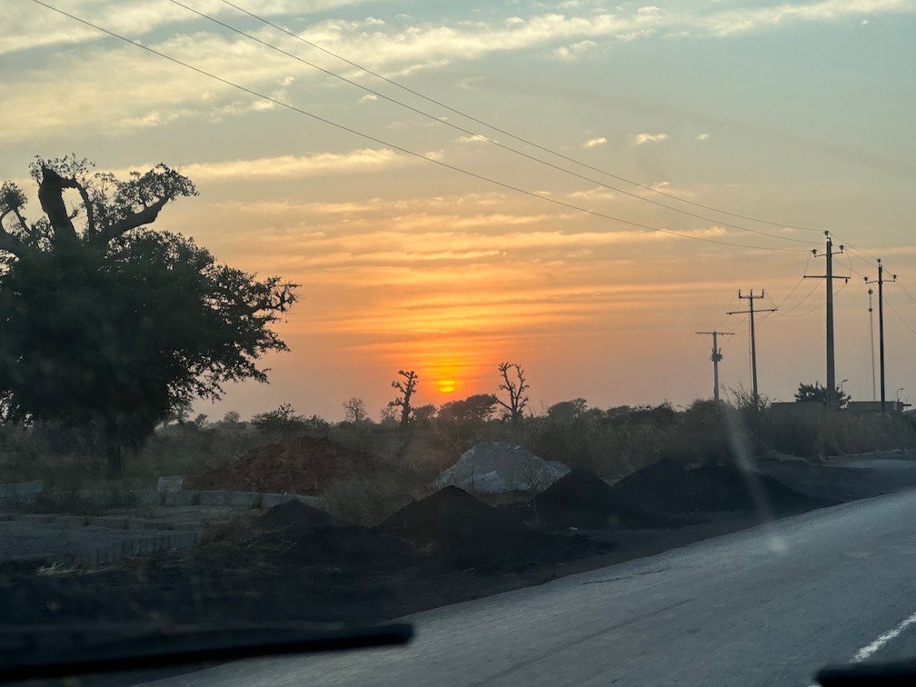 The sun sets over a road with baobab trees in Senegal.