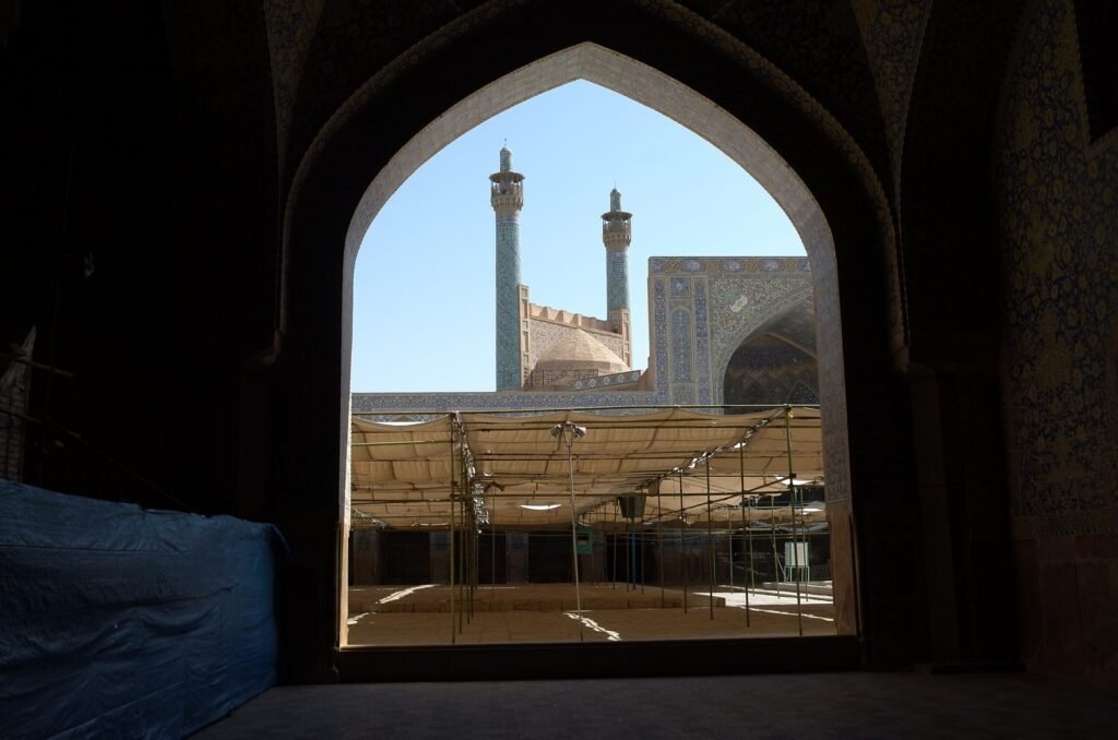 Minarets of the Shah Mosque seen through a dark arch