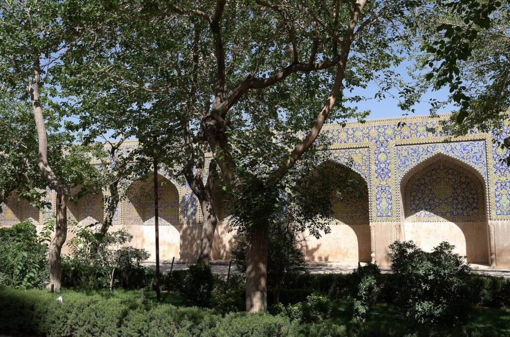 Courtyard with trees and tiled arches at the Shah Mosque
