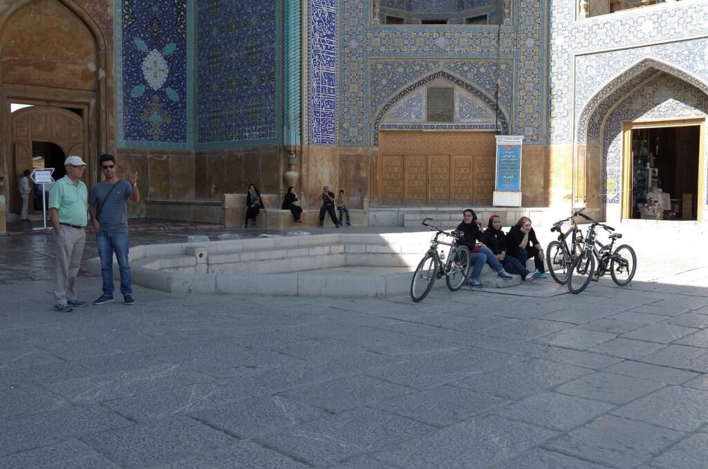 Two visitors in the courtyard of the Shah Mosque, with bicycles