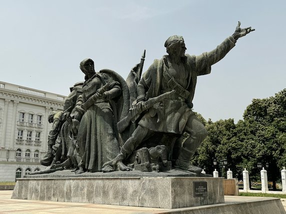 A large bronze monument of fighting figures stands on a stone base in central Skopje.