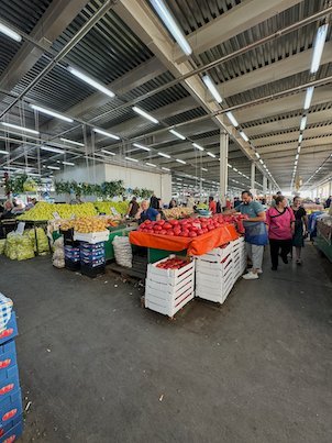 People shop at fruit and vegetable stalls in a large covered market in Skopje.
