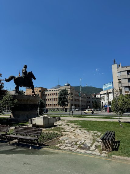 An equestrian statue stands beside park benches in central Skopje.