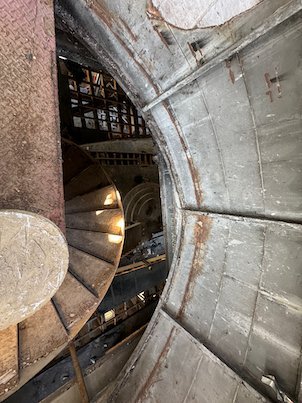 A spiral staircase winds inside the metal hull of a ship structure in Skopje.
