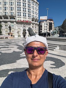 Zayera Khan takes a selfie in sunglasses and a white cap on Macedonia Square in Skopje.