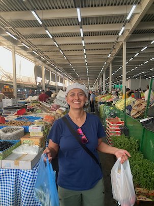 Zayera Khan smiles with shopping bags in a covered market hall in Skopje.