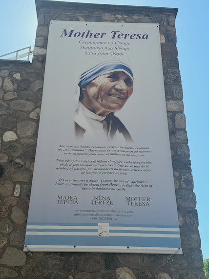 A poster with a portrait of Mother Teresa hangs on a stone wall in Skopje.