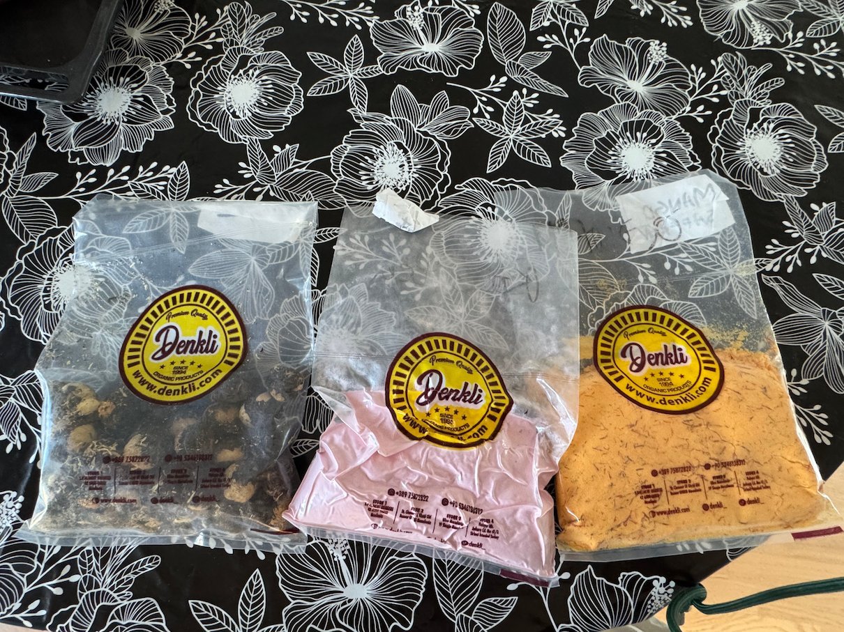 Three bags of loose-leaf tea bought in a shop in Skopje lie on a black floral tablecloth.