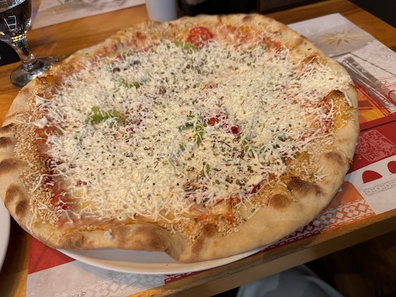 A pizza with tomato sauce and grated cheese sits on a restaurant table in Skopje.