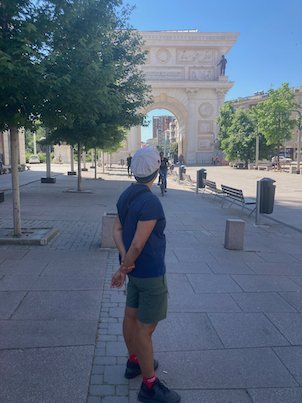 A traveler stands on a street in front of the Porta Macedonia arch in Skopje.