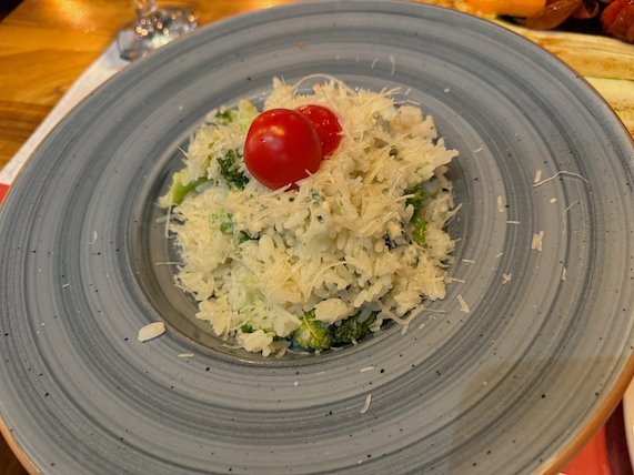 A plate of risotto with cheese and a cherry tomato sits on a table in Skopje.