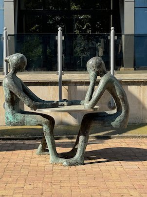 A metal sculpture shows two thin figures sitting at a table in Skopje.