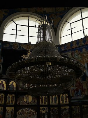 A large chandelier hangs in front of painted icons inside St. Clement of Ohrid Church in Skopje.
