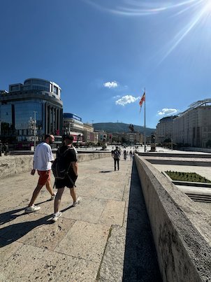 People walk across the Stone Bridge toward the city centre on a sunny day in Skopje.