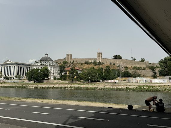 The Vardar riverbank and the walls of Kale Fortress are visible from under a bridge in Skopje.