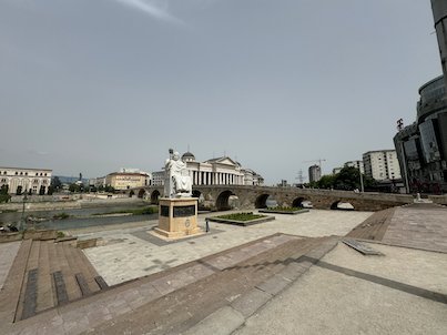 A white statue stands on the riverfront near the Stone Bridge over the Vardar River in Skopje.