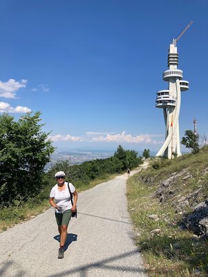 Zayera Khan walks on a mountain road below a tall white tower on Mount Vodno.