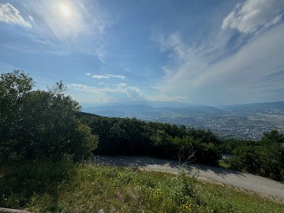 Trees and a mountain road frame a wide view of the valley from Mount Vodno near Skopje.