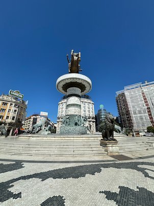 Bronze lions and a patterned pavement surround the Warrior on a Horse fountain in Skopje.