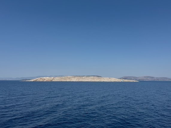 Small low rocky island in the Saronic Gulf, seen from the ferry