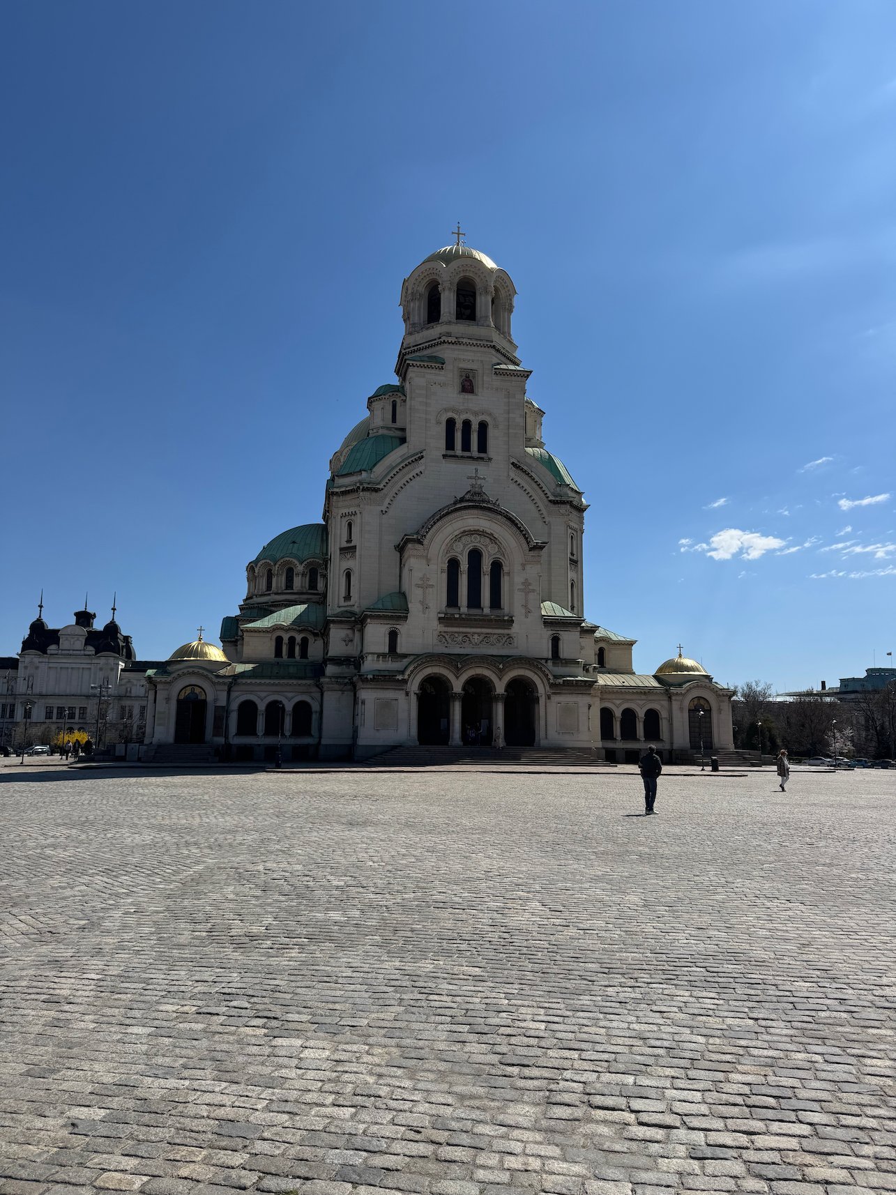 Alexander Nevsky Cathedral rises above a wide cobbled square under a blue sky in Sofia.