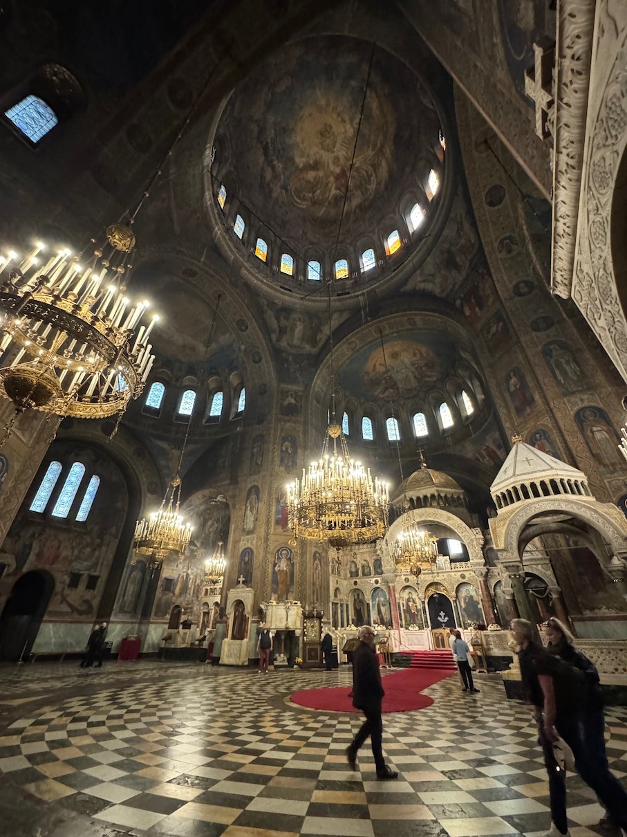 Chandeliers and frescoed domes fill the interior of Alexander Nevsky Cathedral, with a checkered marble floor, in Sofia.