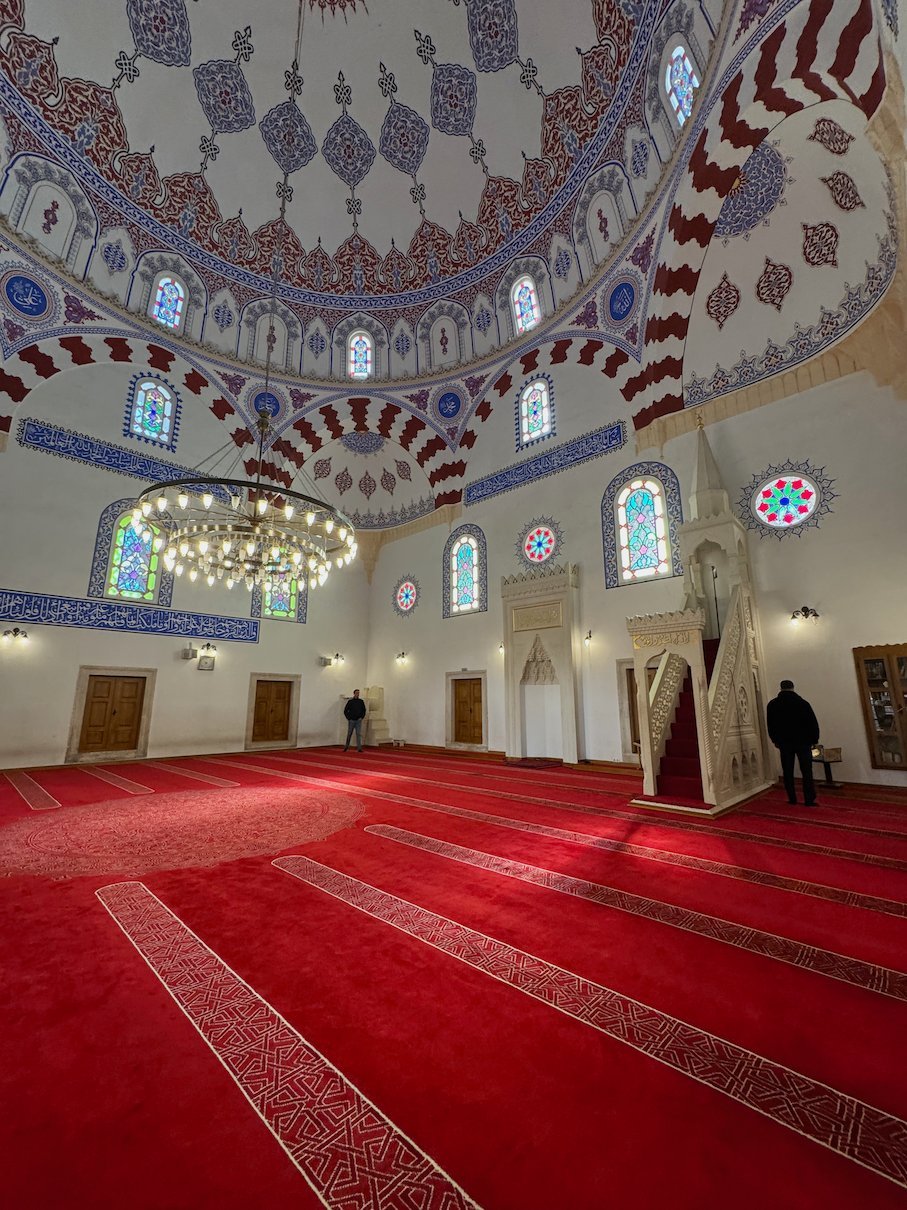 A painted white dome and a red carpet fill the prayer hall of Banya Bashi Mosque in Sofia.