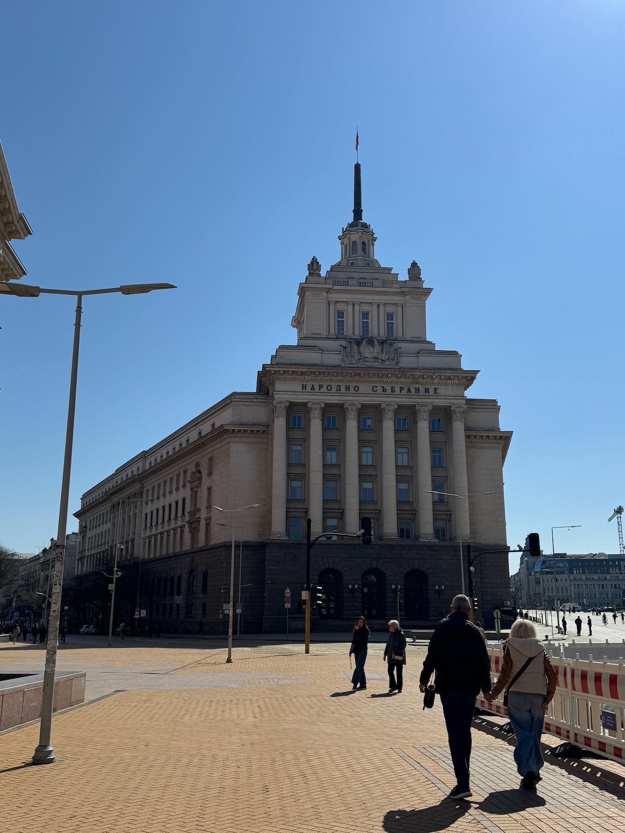 A large Stalinist-style government building with a tall spire stands on the Largo in Sofia.