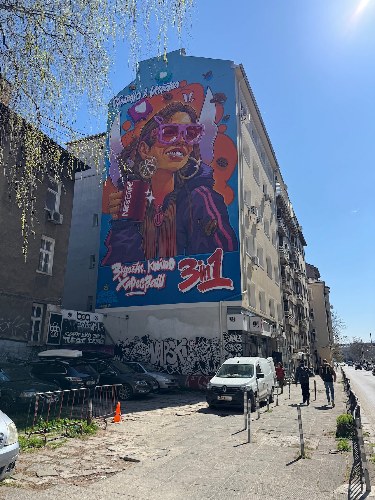 A large pop-art mural of a woman covers the side wall of a building in Sofia.