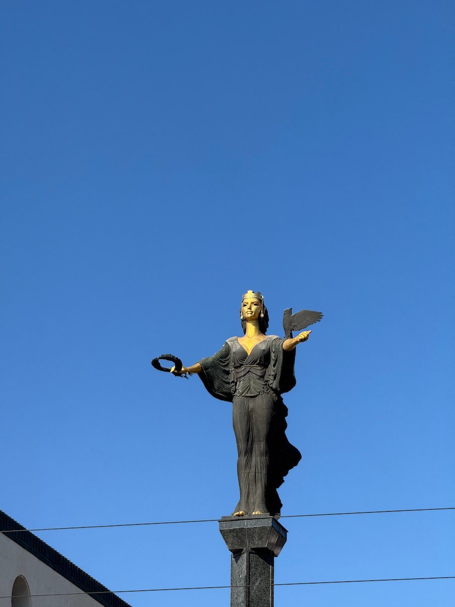 The bronze Statue of Sofia with a gold face and an owl stands on a tall column in Sofia.