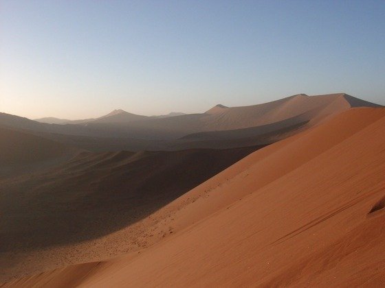 Early light falls on a sharp red dune ridge in the Namib Desert at Sossusvlei.