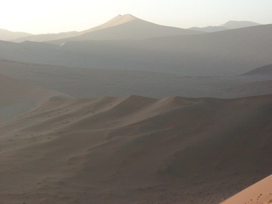 Soft morning haze lies over the dunes and mountains at Sossusvlei in the Namib Desert.