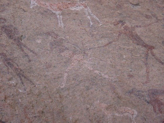 Faded white and red rock paintings cover a granite surface at Spitzkoppe, Namibia.