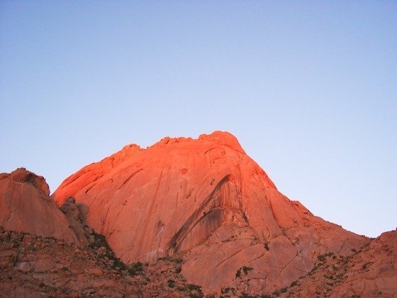The granite peak of Spitzkoppe glows red in the evening sun in Namibia.