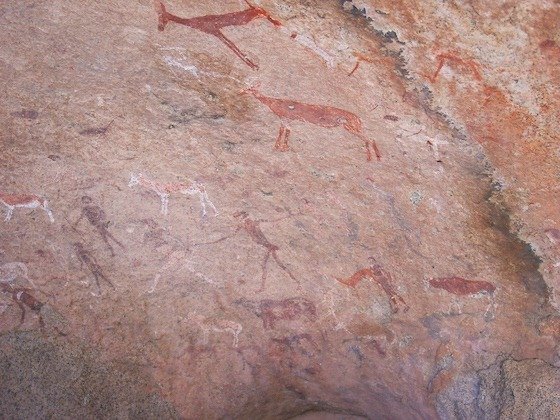 Old rock paintings of animals and people cover a granite wall at Spitzkoppe, Namibia.