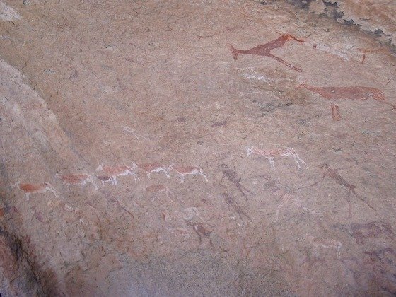 Rock paintings of antelopes and people run across a granite wall at Spitzkoppe, Namibia.