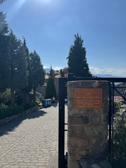 Paved path and a gate with a plaque at St. Stephen's Monastery, Meteora