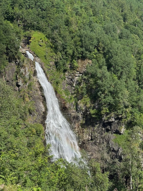 Waterfall that falls through green forest below Stalheim
