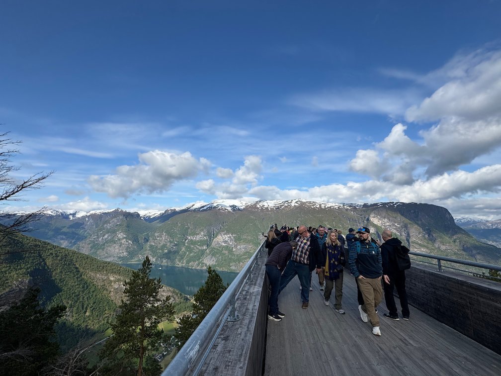 Visitors on the Stegastein viewpoint platform above the Aurlandsfjord, with snowy mountains