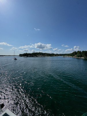 Ferry wake on dark water and a sailboat in the distance