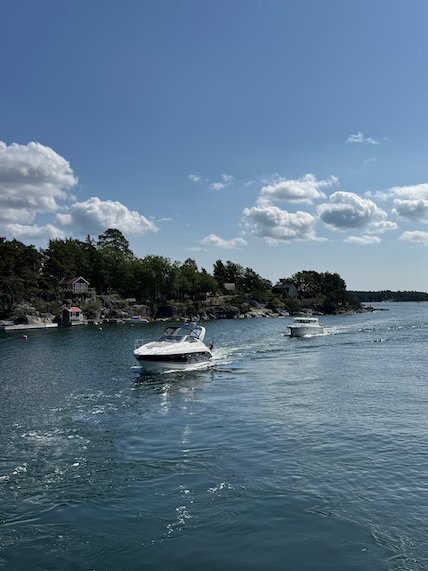 Motorboats between wooded islands, seen from the ferry to Möja